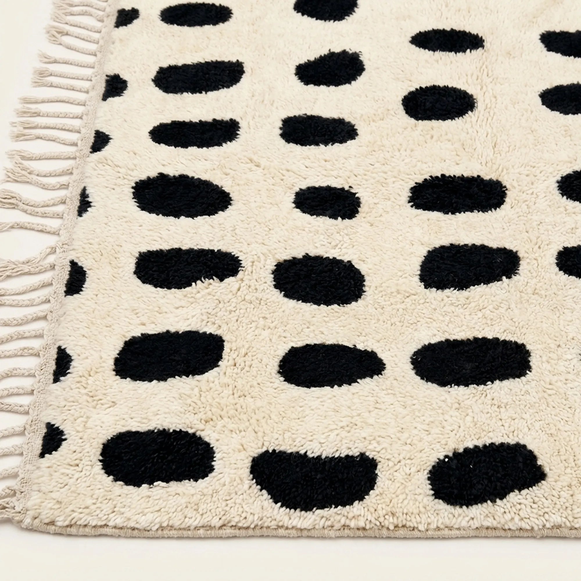 Angled view of the Tissa ivory and black Beni Ourain rug showing the oval grid design.