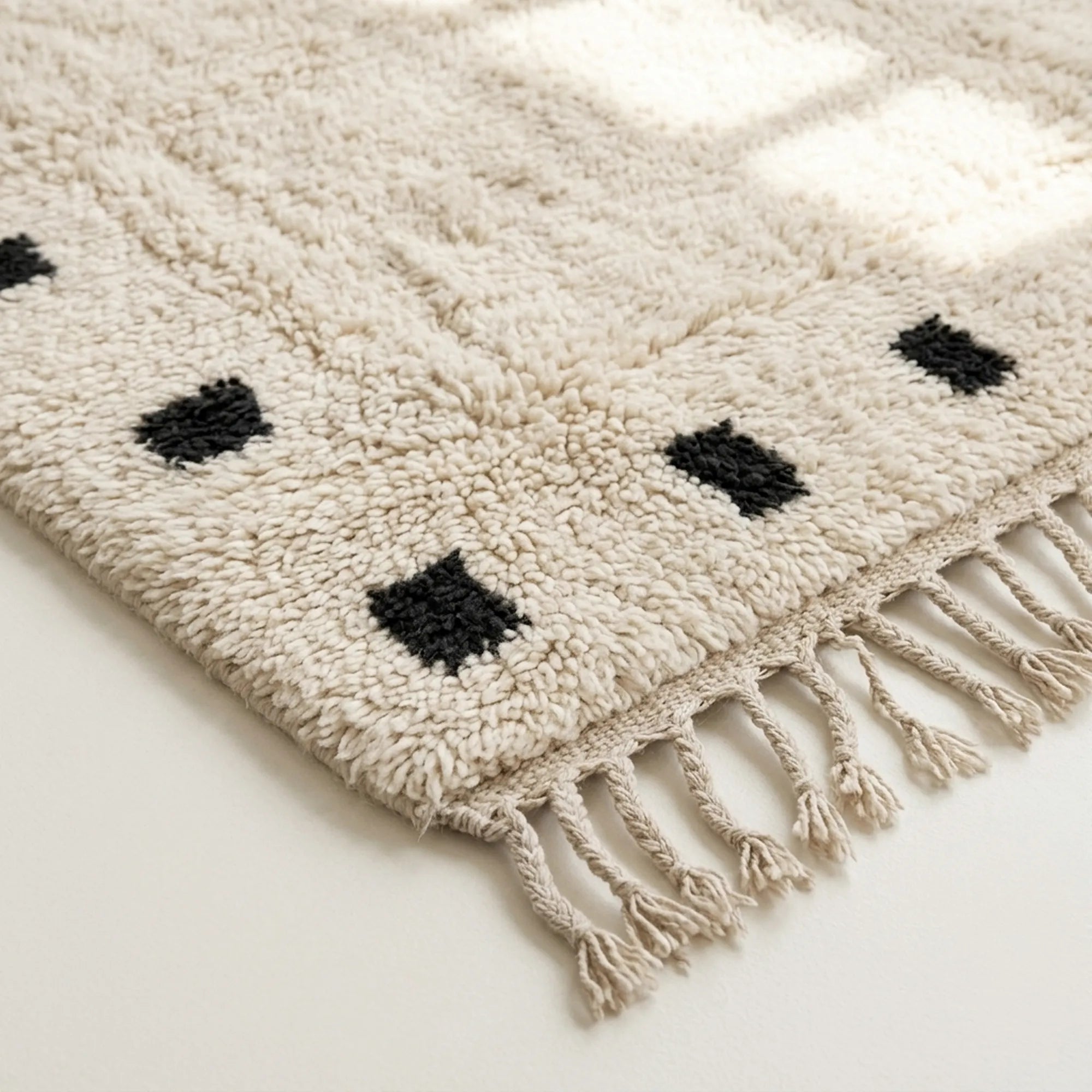 Angled detail of the ivory and black hand-knotted wool rug.