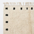 Natural wool pile detail on the ivory and black square border rug.