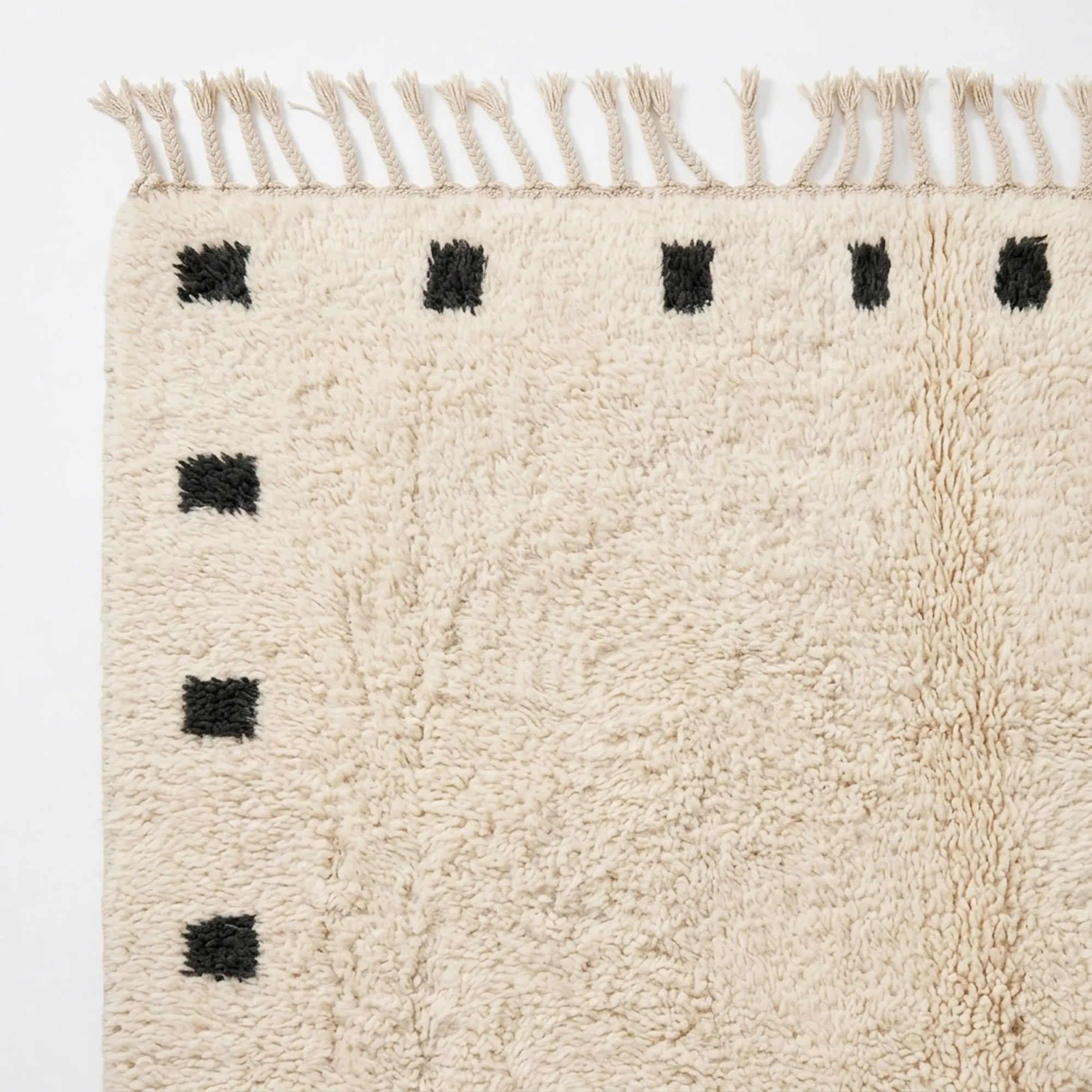 Natural wool pile detail on the ivory and black square border rug.