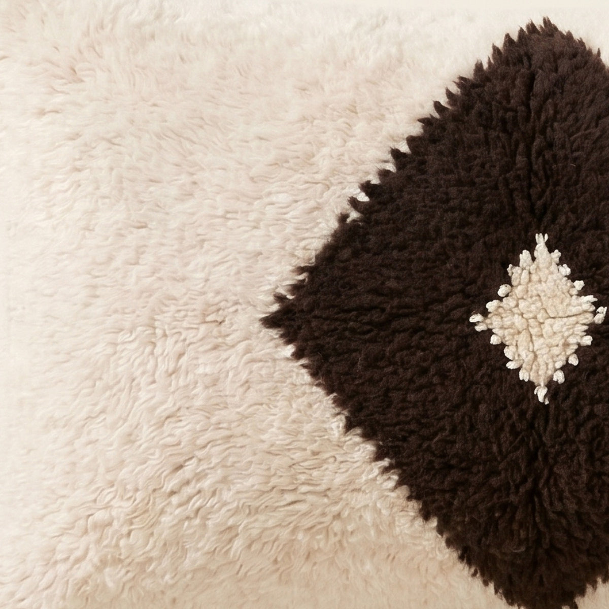 Side view of the Tit Moroccan pillow showing its ivory and black wool pile
