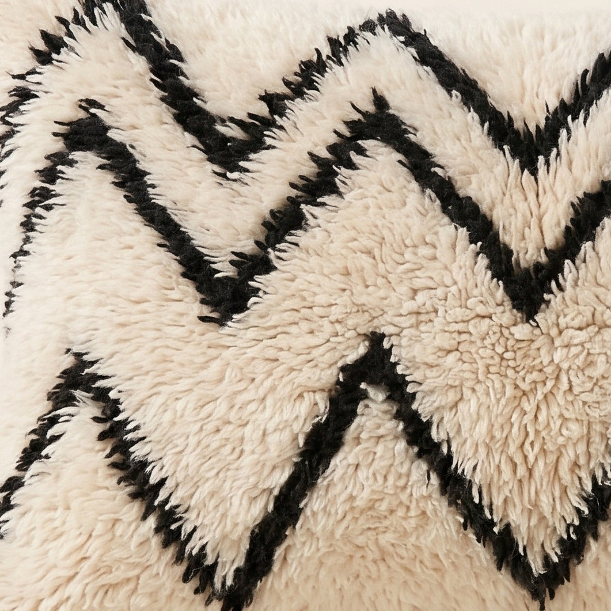 Side view of the Aman Moroccan pillow showing its ivory and black wool pile
