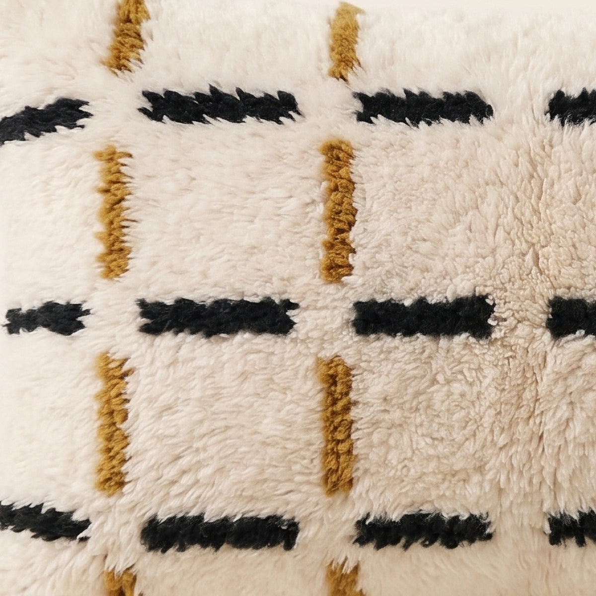 Side view of the Tazart Moroccan pillow showing its ivory, black and mustard wool pile