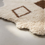 Side angle showing pile depth and fringe edge of ivory Beni Ourain rug