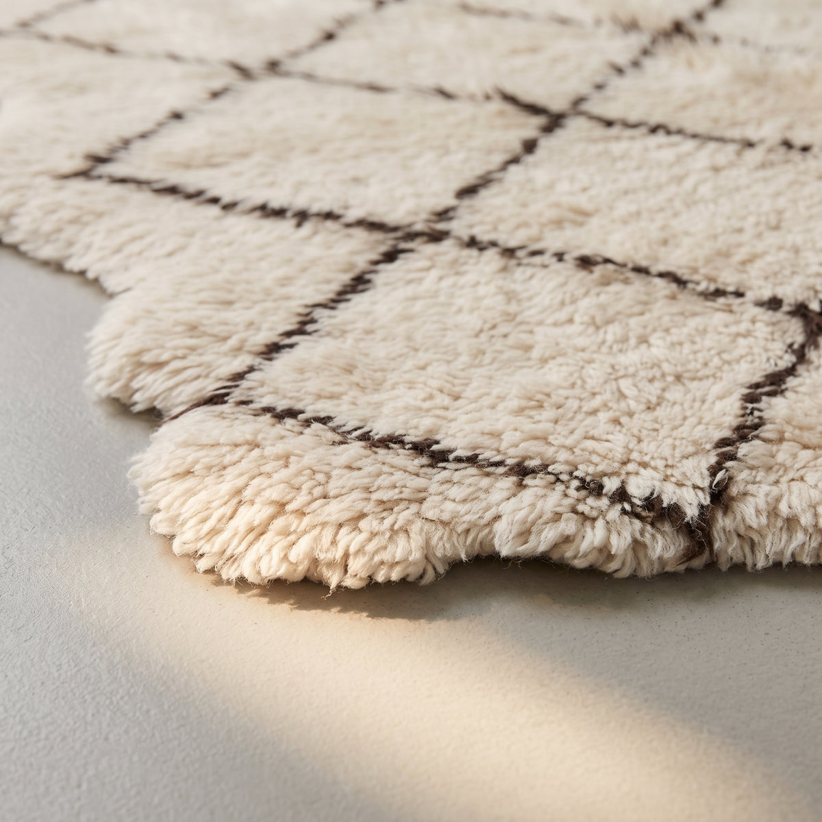 Side angle showing pile depth and fringe edge on ivory Beni Ourain Ifri rug