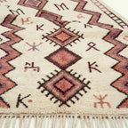 Close view of the burgundy geometric diamond pattern on an ivory Azilal rug