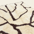 Close-up of the burgundy branch line pattern on the Mazigh ivory Beni Ourain rug.