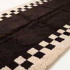 Close-up of hand-knotted wool pile texture showing checkerboard pattern detail