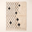 Ivory & Charcoal Beni Ourain rug with black diamond lattice and scattered black diamond accents on plain background