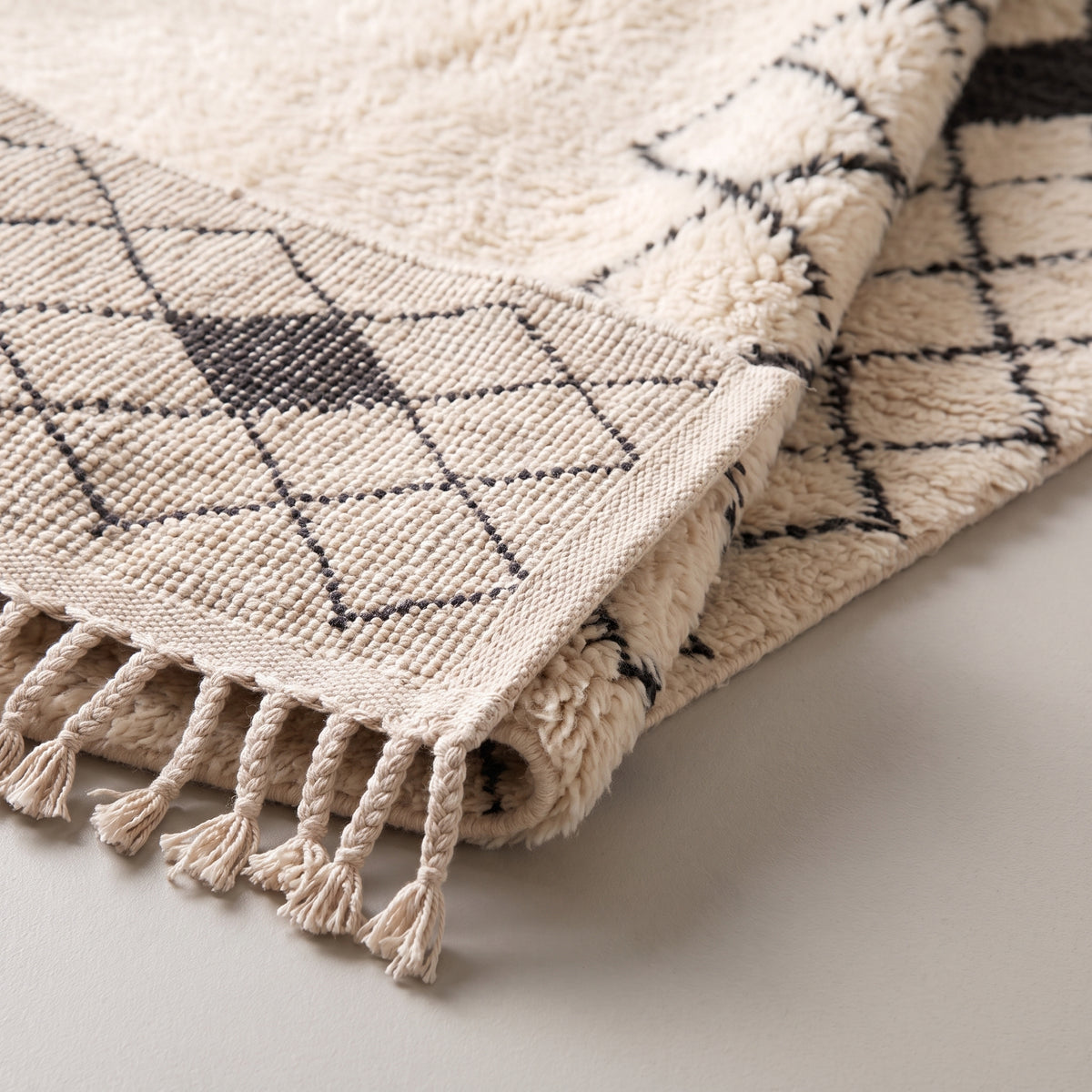 Close-up of Ivory & Charcoal Beni Ourain rug edge showing woven fringe and lattice detail