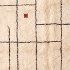 Close-up detail revealing rust red accent and woven grid pattern in wool pile