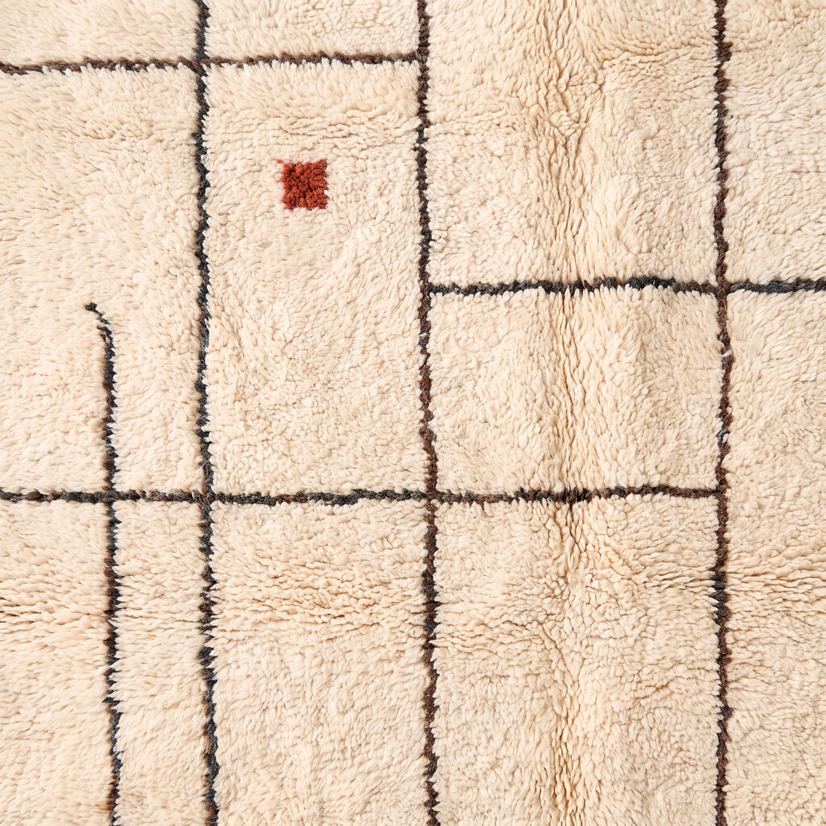 Close-up detail revealing rust red accent and woven grid pattern in wool pile
