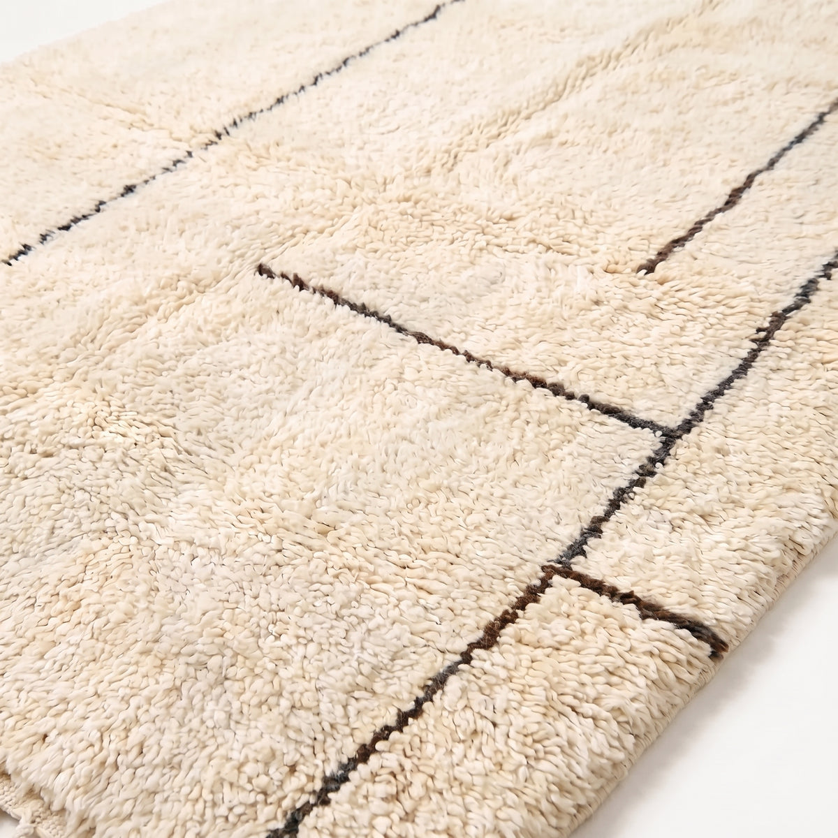 Close-up of soft hand-knotted wool pile showing charcoal grid lines dividing blocks