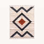 Ivory Beni Ourain rug with nested charcoal diamond borders and terracotta central diamond, flat lay on pale background