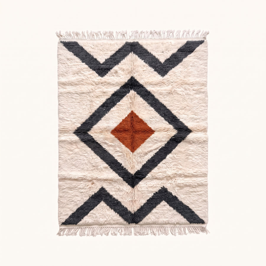 Ivory Beni Ourain rug with nested charcoal diamond borders and terracotta central diamond, flat lay on pale background