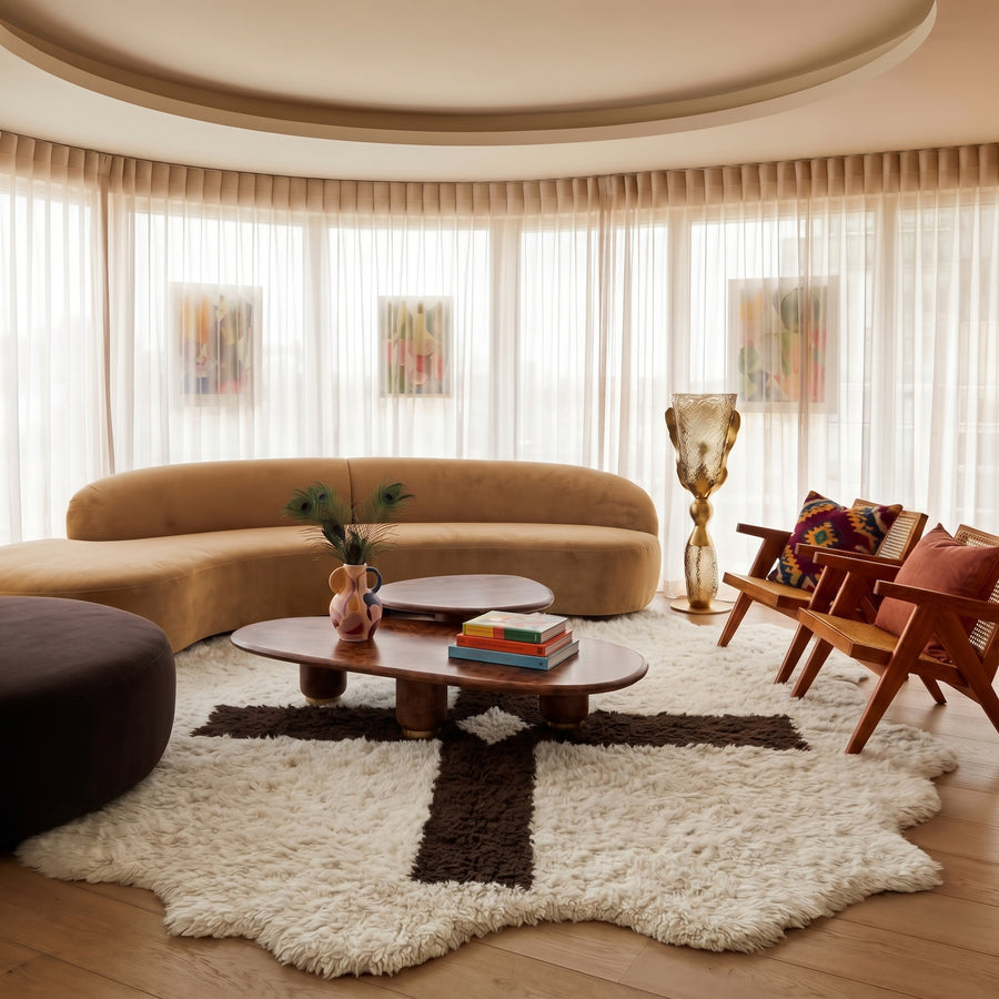 Ivory and dark brown Beni Ourain rug styled in contemporary living room with curved sofa and wood furniture