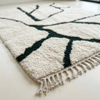 Angled view of the Tazla ivory and forest green Beni Ourain rug showing the branch line design.