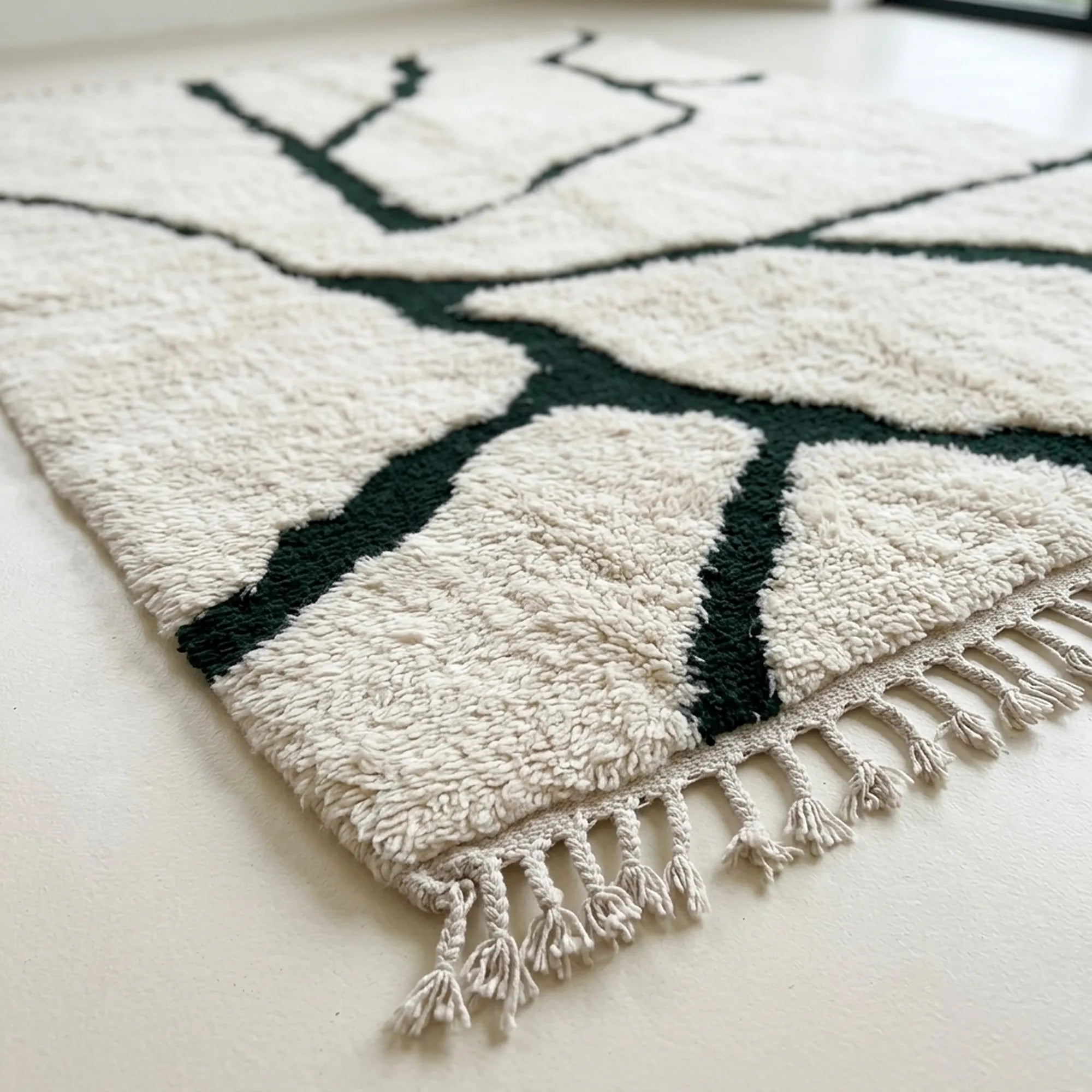 Angled view of the Tazla ivory and forest green Beni Ourain rug showing the branch line design.