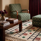 Ayyur Beni Ourain rug in living room with wood furniture, green patterned chair and maroon flowers