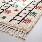 Angled detail of knotted pile showing depth and weave structure with terracotta, green and black geometric elements