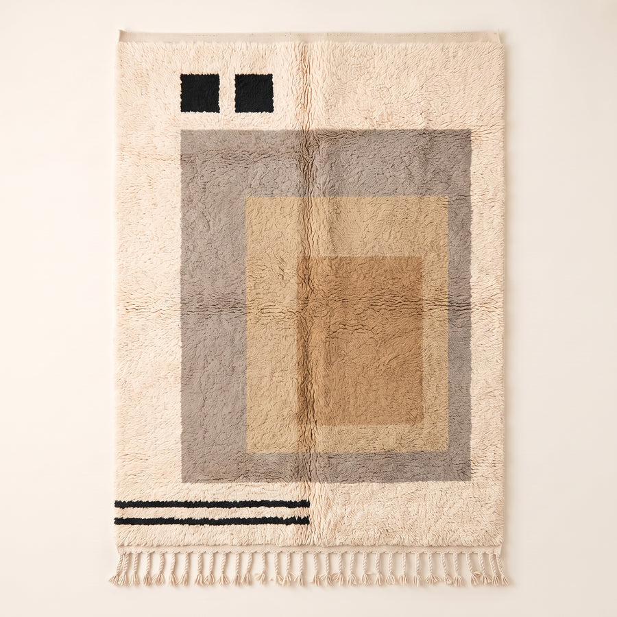 Ivory, grey and sand Beni Ourain rug with nested rectangular frames and black accent squares, flat lay on plain background