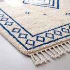 Corner of rug showing navy diamond border and soft pile construction