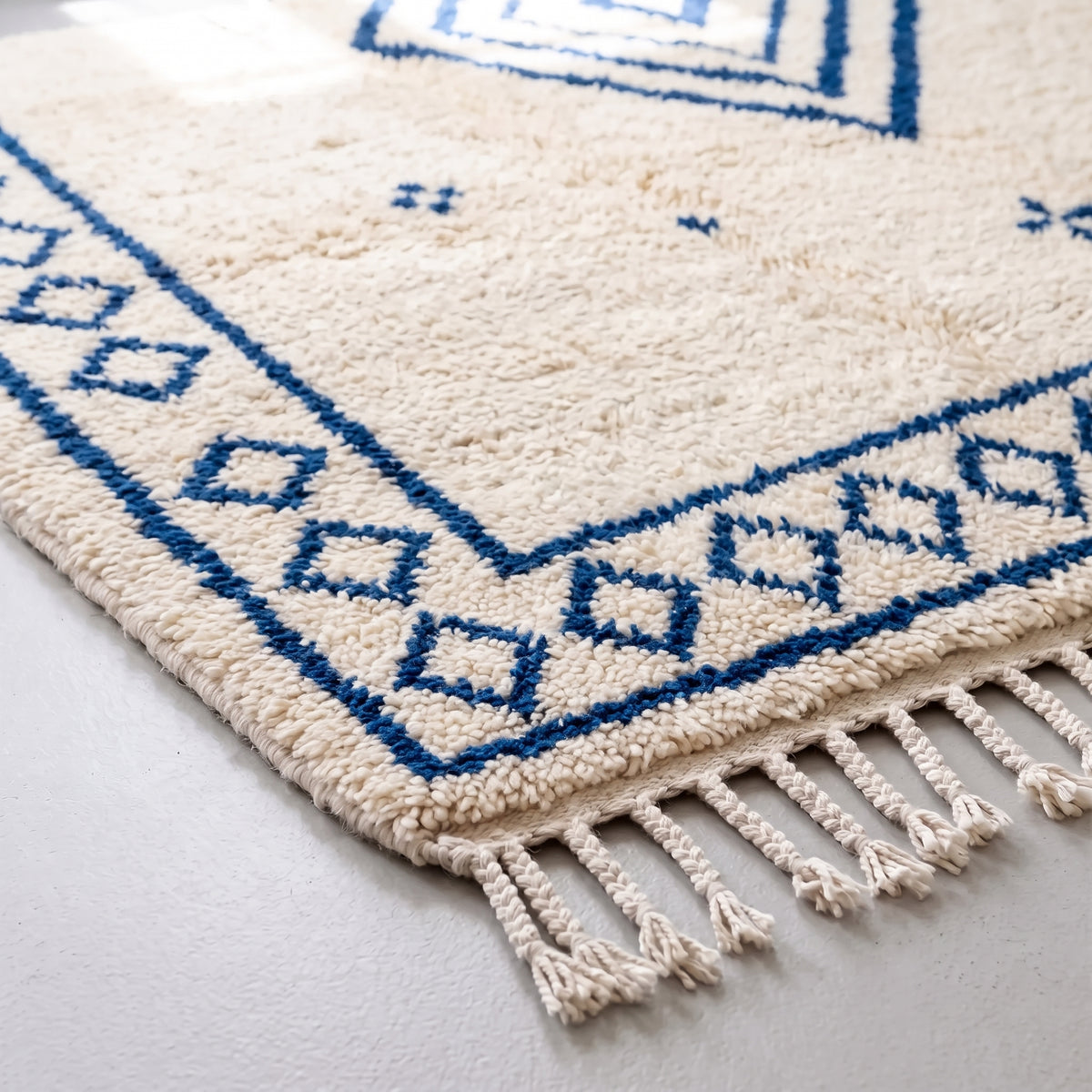 Corner of rug showing navy diamond border and soft pile construction