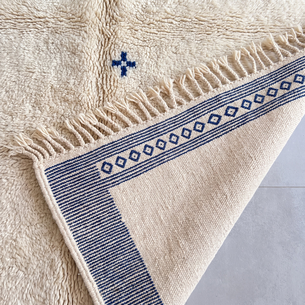 Pile texture and fringe edge showing thick wool construction and navy patterning