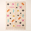 Ivory Azilal rug with scattered magenta, teal, orange, black and gold symbols including crosses, X marks, zigzags, triangles and combs on a cream ground, flat lay