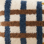Side view of the Tamda Moroccan pillow showing its ivory, navy and brown wool pile