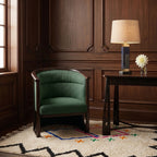 Ivory Azilal rug with diamond pattern layered in a wood-paneled room beneath a green chair and dark desk