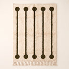 Ivory and olive Beni Ourain rug with five lollipop rail motifs featuring dark olive circles at top and bottom connected by thin vertical rails on cream ground, flat lay on plain background