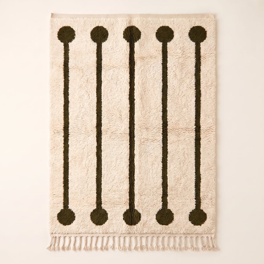 Ivory and olive Beni Ourain rug with five lollipop rail motifs featuring dark olive circles at top and bottom connected by thin vertical rails on cream ground, flat lay on plain background