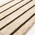 Close-up of ivory and olive Beni Ourain rug showing thick soft pile texture and the fine detail of olive rails against ivory ground
