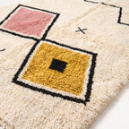 Close-up of broken diamond motif showing thick wool pile texture and color contrast between rose, gold and teal