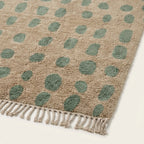 Angled view of the Taddart ivory and sage green Beni Ourain rug showing the oval grid design.