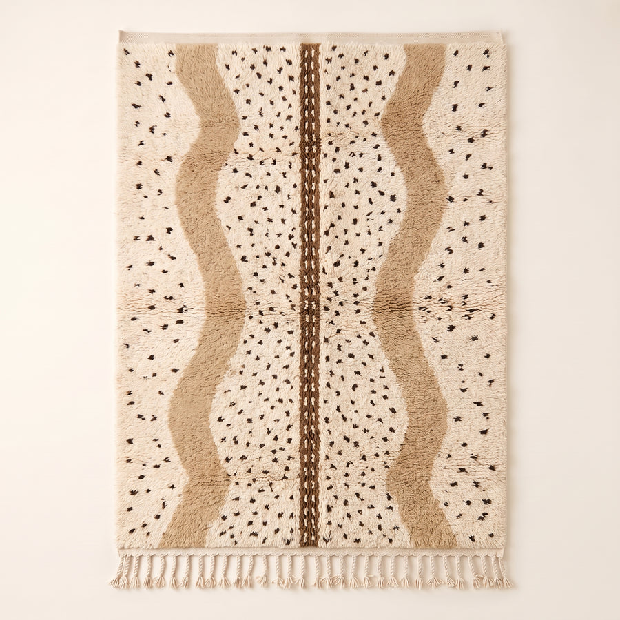 Ivory and tan Beni Ourain rug with scattered black diamonds and warm tan vertical panels with brown center band, flat lay on neutral background