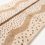 Close-up of Beni Ourain weave showing scattered black diamonds, tan and ivory wool pile with brown center band detail
