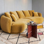 Ivory, gold, navy and terracotta Beni Ourain rug in living room under curved yellow sofa with glass side table