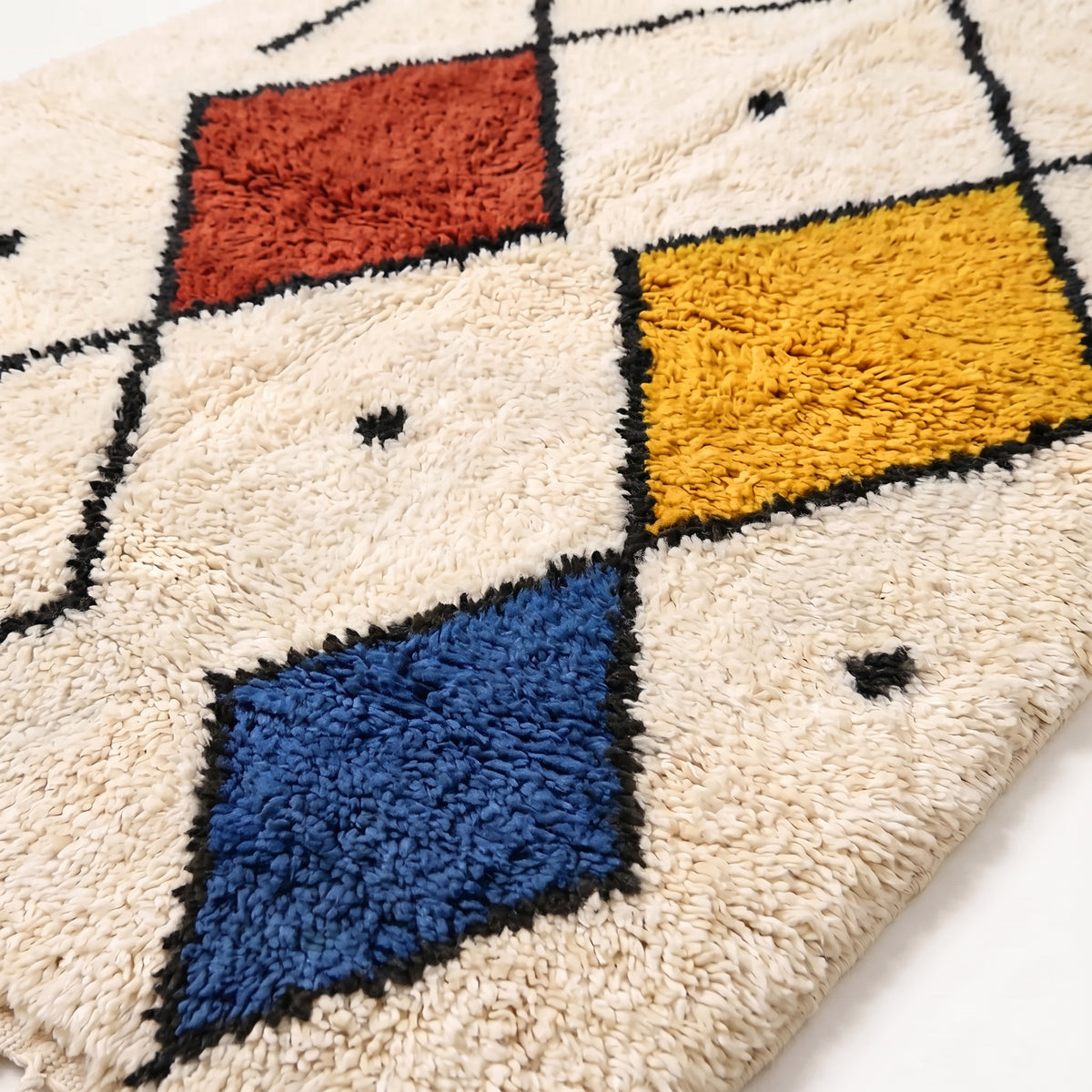 Close-up of Tiziri rug pile showing terracotta, gold, navy diamond details and soft ivory wool texture
