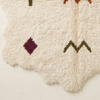 Corner and edge detail showing wavy irregular fringe and burgundy diamond symbol near rug edge