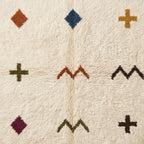 Full-field pile texture close-up displaying scattered terracotta diamond, navy diamond, gold cross, and olive cross against ivory ground