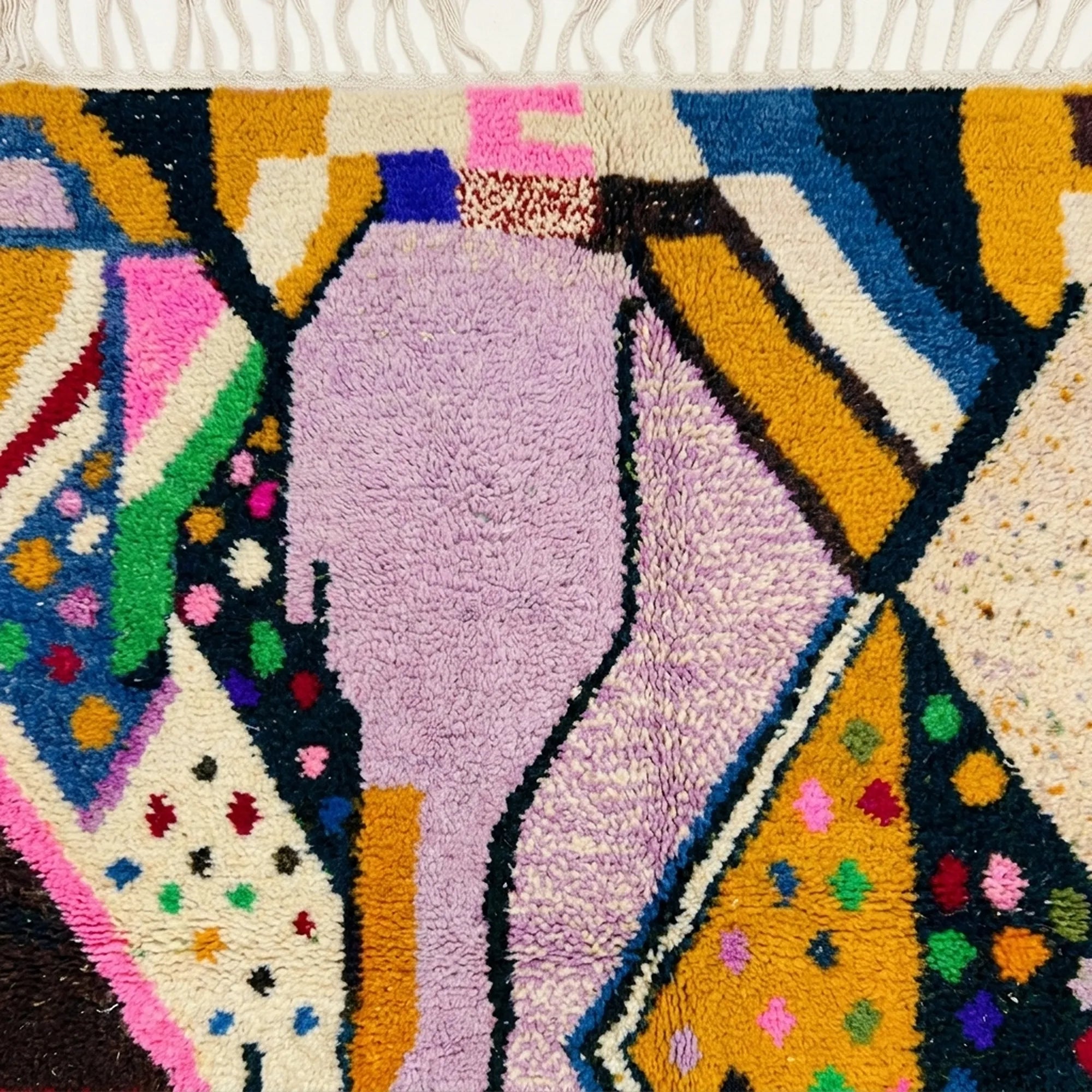 Detailed view of Tamsa showing graphic black lines and bright woven accents across lilac and mustard wool