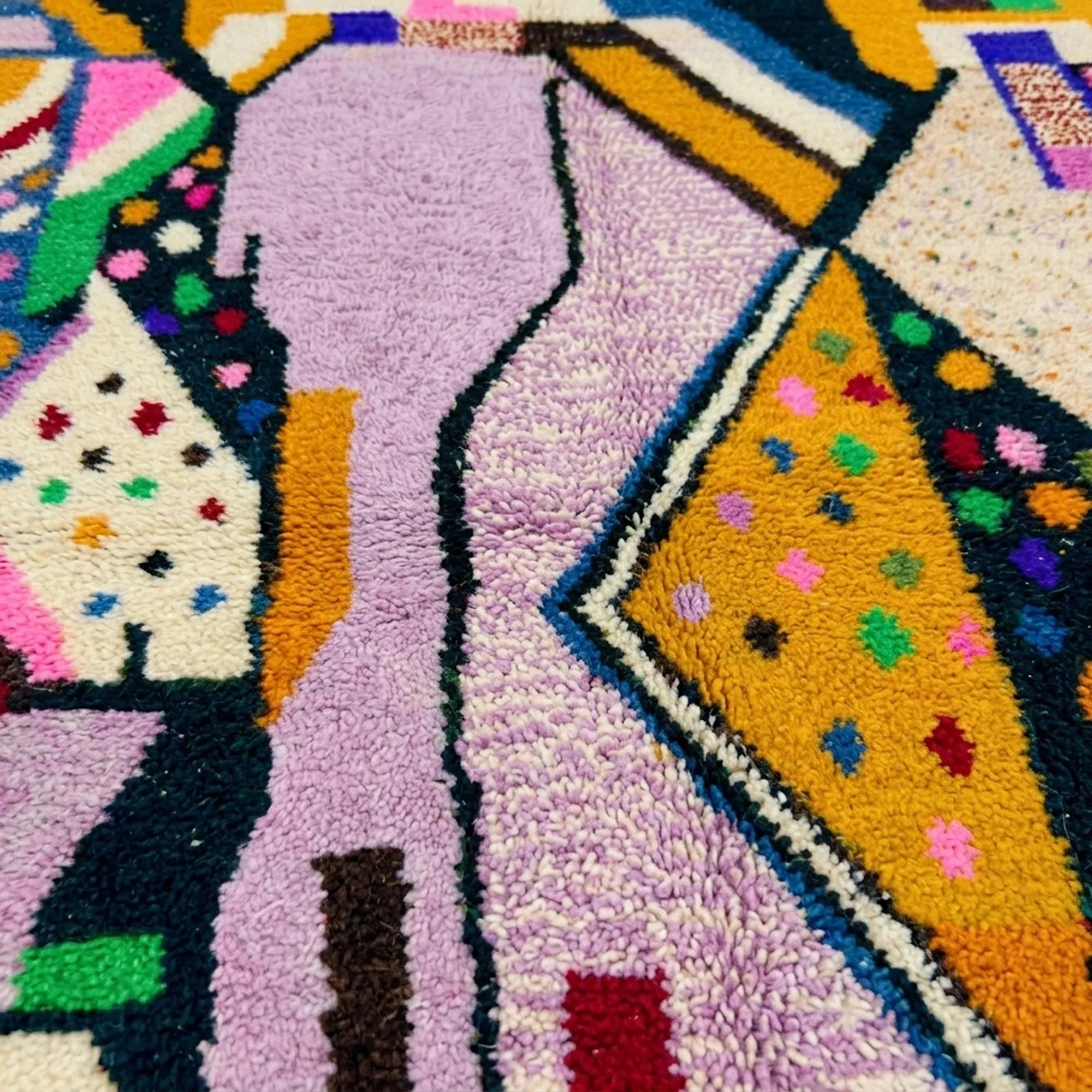 Lower-edge detail of the Tamsa Boujaad rug showing angular lilac, mustard, black and green shapes