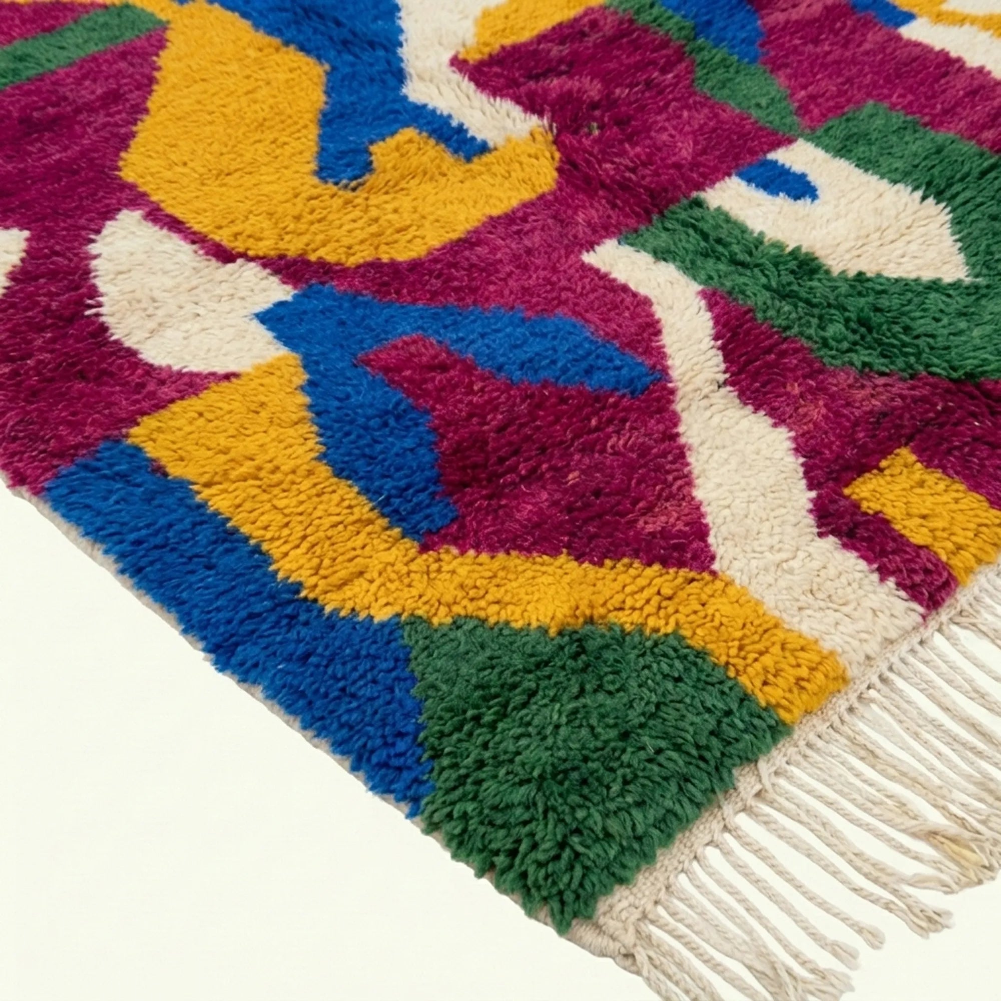 Fringe and edge detail of Amzagh beside saturated magenta, green, cobalt and cream shapes