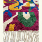 Lower edge close-up of the Amzagh Boujaad rug showing green and magenta fields with cream accents