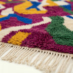 Detail view of Amzagh showing the handwoven transition between magenta, mustard, cobalt and green motifs
