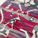 Pattern close-up of Azemur showing angular cream lines, symbolic forms and dark accents across a magenta and gray field