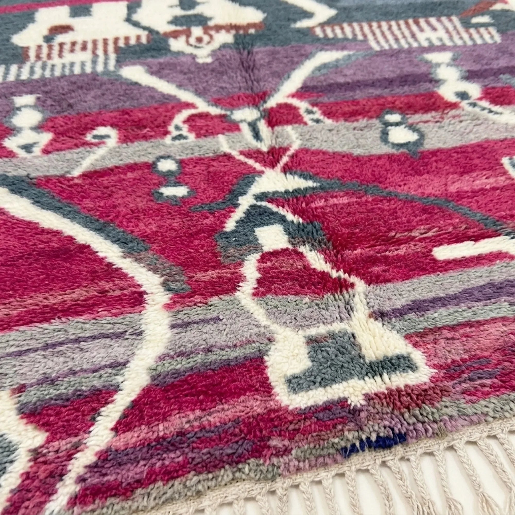 Close-up of the Azemur Boujaad rug showing plush magenta and gray wool with cream geometric lines