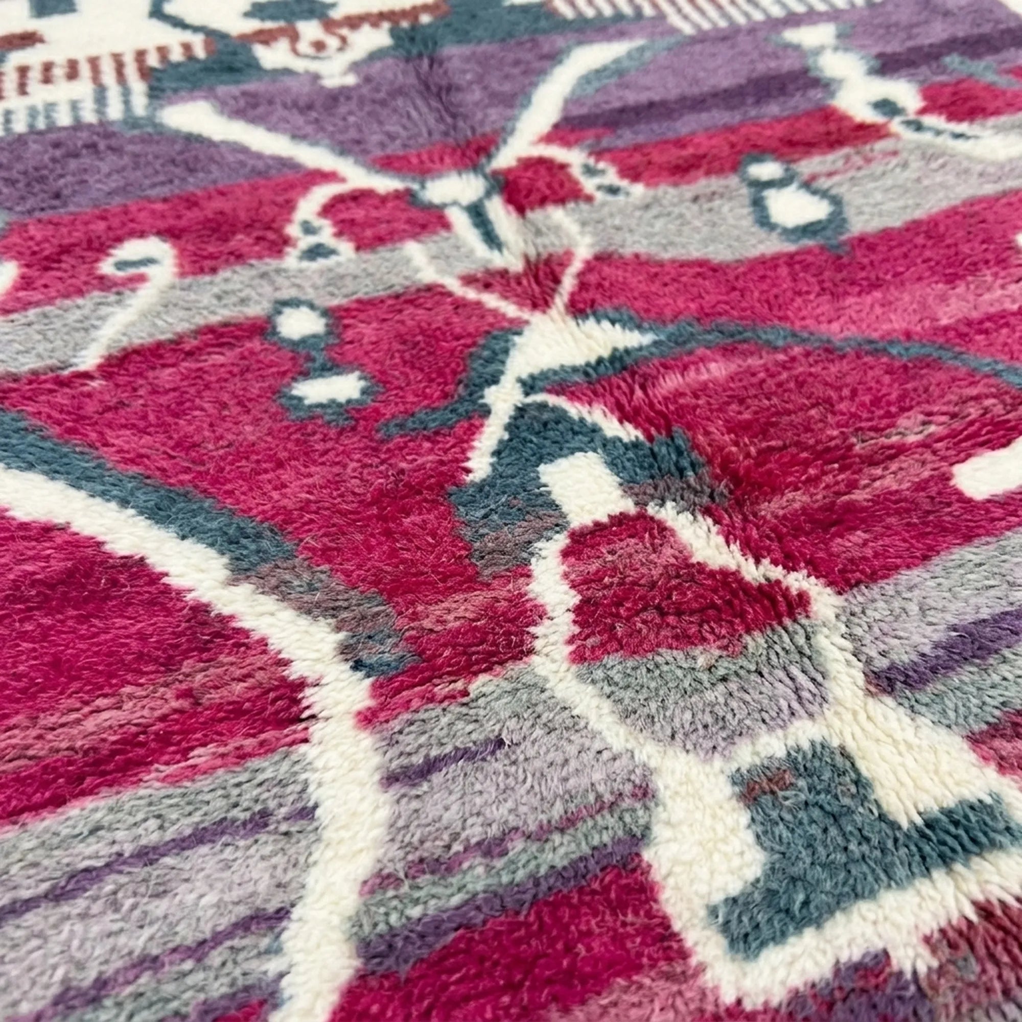 Fringe and edge detail of the Azemur Boujaad rug beside magenta, gray and cream symbolic bands
